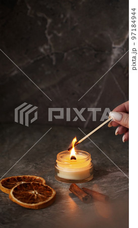 A woman hand holds a long match to light a homemade candle A woman hand holds a long match to light a homemade candle 97184944