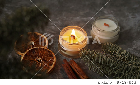 Candle in a glass with slices of orange, cinnamon sticks and fir branches. 97184953