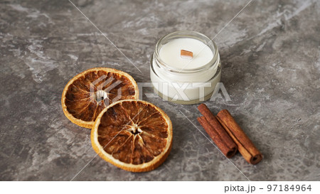 Handmade candle with wooden wick in glass jar with cinnamon and dry oranges 97184964