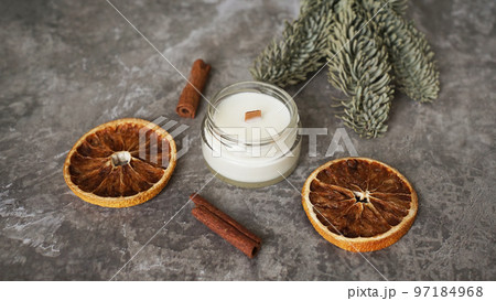 Candle in a glass with slices of orange, cinnamon sticks and fir branches. 97184968