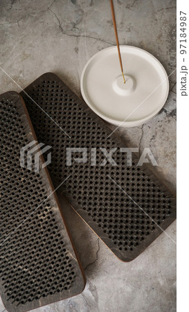 Incense on a white ceramic stand and boards with nails for yoga classes. 97184987