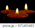 Composition of three candles on dark luxury night background. Black table, side view. Candles Burning at Night. Orange taper burning in focus, foreground. illustration design. 97185483