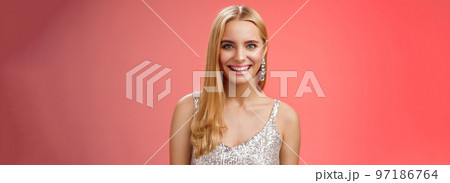 Charming glamour fabulous adult 25s blond woman in elegant silver dress shiny earrings smiling happily take part interesting conversation talking look friendly grinning, standing red background Charming glamour fabulous adult 25s blond woman in elegant silver dress shiny earrings smiling happily take part interesting conversation talking look friendly grinning, standing red background 97186764