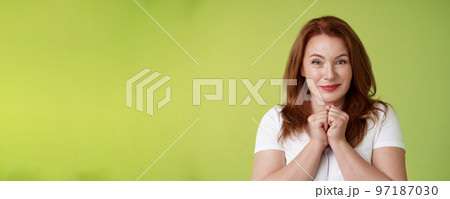 Cheerful lovely pleasant redhead middle-aged female press hands together delight kind happy gaze smiling joyfully touched grateful receive heartwarming gift look admiration happiness 97187030