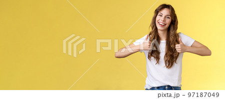 Outgoing positive confident lively young girl long curly haircut support great effor show thumbs up positive reply approving good choice like your outfit smiling broadly yellow background Outgoing positive confident lively young girl long curly haircut support great effor show thumbs up positive reply approving good choice like your outfit smiling broadly yellow background 97187049