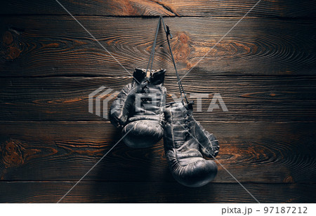 Old boxing gloves hanging on nail on wooden wall Old boxing gloves hanging on nail on wooden wall 97187212