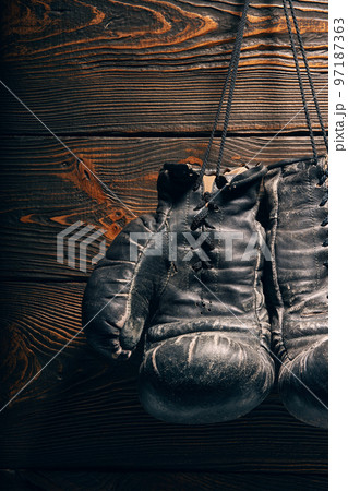 Old boxing gloves hanging on nail on wooden wall. 97187363