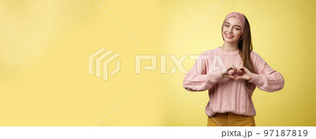 Girl brings peace and love, smiling tender, lovely showing heart gesture over chest, adoring, liking making romantic gestures feeling sympathy, passion and romance in air, posing in sweater Girl brings peace and love, smiling tender, lovely showing heart gesture over chest, adoring, liking making romantic gestures feeling sympathy, passion and romance in air, posing in sweater 97187819