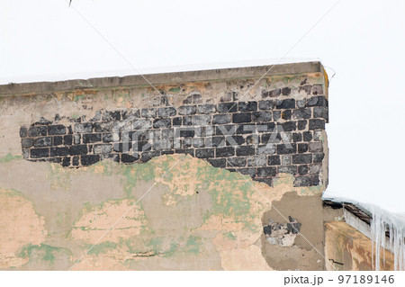 A shabby wall with burnt bricks and icicles on the edge. A shabby wall with burnt bricks and icicles on the edge. 97189146