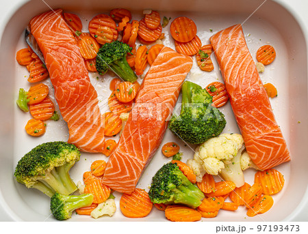 Top view of baking dish casserole with raw uncooked fish salmon steaks, broccoli, cauliflower, carrot. Preparing a healthy dinner concept Top view of baking dish casserole with raw uncooked fish salmon steaks, broccoli, cauliflower, carrot. Preparing a healthy dinner concept 97193473