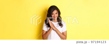 Image of cunning african-american girl, rubbing hands and smiling pleased, relish good deal, standing over yellow background Image of cunning african-american girl, rubbing hands and smiling pleased, relish good deal, standing over yellow background 97194123