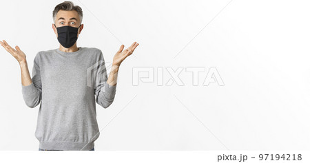 Covid-19, pandemic and social distancing concept. Portrait of handsome middle-aged man in black medical mask looking surprised, reacting amazed, standing over white background Covid-19, pandemic and social distancing concept. Portrait of handsome middle-aged man in black medical mask looking surprised, reacting amazed, standing over white background 97194218