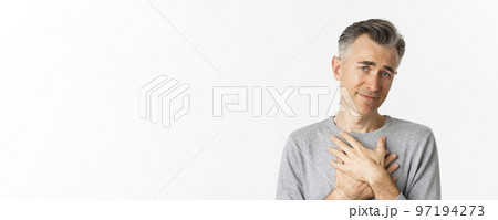 Close-up of thankful middle-aged man, holding hands on heart and feeling touched, appreciate kind gesture, standing over white background Close-up of thankful middle-aged man, holding hands on heart and feeling touched, appreciate kind gesture, standing over white background 97194273