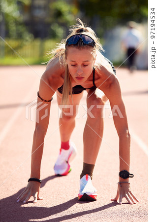 Woman getting ready to start on Stadium - summer outdoors training. Woman getting ready to start on Stadium - summer outdoors training. 97194534