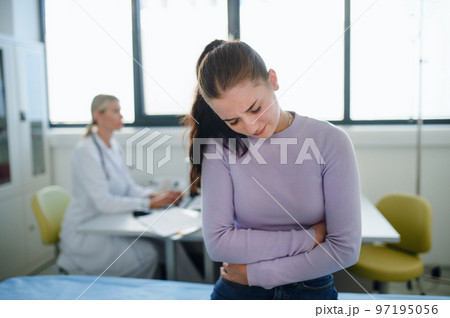 Teenage girl with stomach ache sitting in doctor's office. 97195056