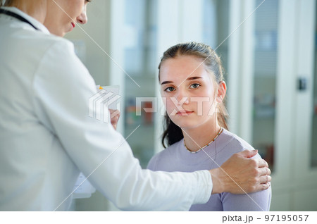 Close-up of doctor consoling unhappy teenage girl in her ambulance office. 97195057