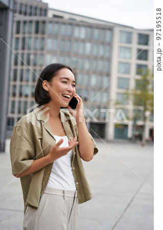 Vertical shot of smiling stylish asian girl, having a telephone conversation and walking on street. Young woman talking on mobile phone Vertical shot of smiling stylish asian girl, having a telephone conversation and walking on street. Young woman talking on mobile phone 97195518