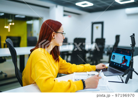 Female blogger with laptop recording video while sitting at office and talking about startup business. Female blogger with laptop recording video while sitting at office and talking about startup business. 97196970