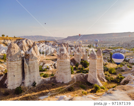 Colorful hot air balloons flying over at fairy chimneys valley in Nevsehir, Goreme, Cappadocia Turkey. Spectacular panoramic drone view of the underground city and ballooning tourism. High quality Colorful hot air balloons flying over at fairy chimneys valley in Nevsehir, Goreme, Cappadocia Turkey. Spectacular panoramic drone view of the underground city and ballooning tourism. High quality 97197139