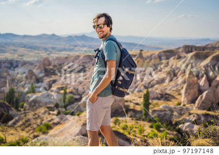 Young man exploring valley with rock formations and fairy caves near Goreme in Cappadocia Turkey Young man exploring valley with rock formations and fairy caves near Goreme in Cappadocia Turkey 97197148