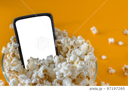 Mobile phone and popcorn in a bowl, on a yellow...の写真素材 [97197260] - PIXTA