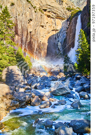 Yosemite Falls with frosty waters over rocks and rainbow 97197359