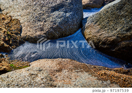 Unusual wavy ice pattern between rocks in detail Unusual wavy ice pattern between rocks in detail 97197539