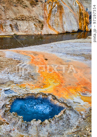 Vibrant blue Chinese with orange sediment runoff into river at Yellowstone Vibrant blue Chinese with orange sediment runoff into river at Yellowstone 97197554
