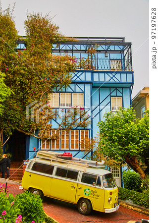 Volkswagen bus on steep brick road next to blue west coast home Volkswagen bus on steep brick road next to blue west coast home 97197628