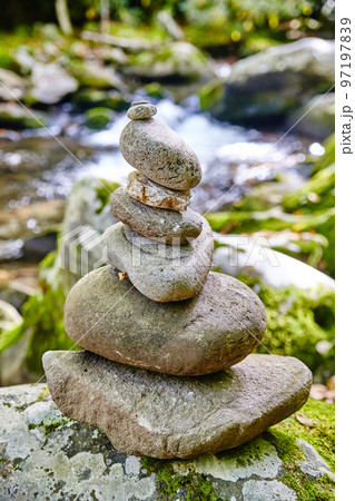 Stack of smooth rocks with a river in the background 97197839