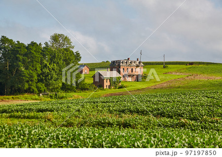Landscape shot of a red brick mansion from a distance with green farmland in the foreground and a forest in the middle ground Landscape shot of a red brick mansion from a distance with green farmland in the foreground and a forest in the middle ground 97197850