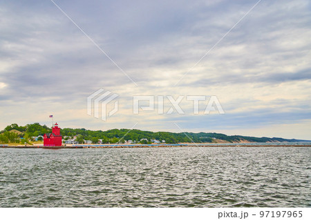 View of red lighthouse with large lake and beach houses in distance 97197965