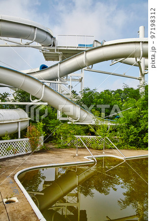 Brown water pool with a massive water slide in the background in an abandoned theme park Brown water pool with a massive water slide in the background in an abandoned theme park 97198312
