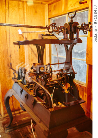 Close-up of an antique machine in a wooden room with orange lighting 97198457