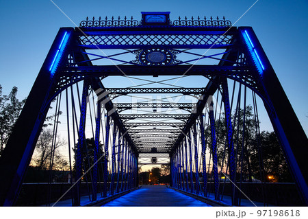 Metal bridge glows blue while backlit by the setting sun 97198618