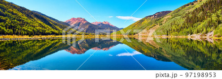 Panorama of lake in the mountains surrounded by fall trees and red sandy mountain peaks 97198953