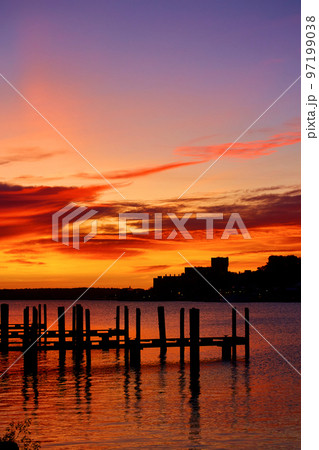 Golden red sunrise with docks sitting in a rive with ripples of water 97199038