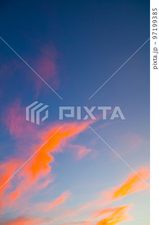 Neon orange thin wispy clouds on a blue sky 97199385
