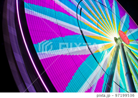 Ferris wheel fully lit up at night with pinks and blues and grays in a compass like design Ferris wheel fully lit up at night with pinks and blues and grays in a compass like design 97199536