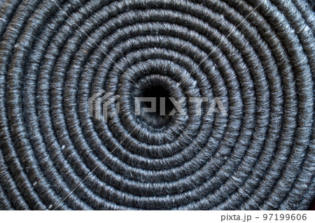 Relief texture of rolled up grey carpet as background. Close up of coiled natural dark rope, jute spiral circle pattern from above. Concept of textures and backgrounds. Relief texture of rolled up grey carpet as background. Close up of coiled natural dark rope, jute spiral circle pattern from above. Concept of textures and backgrounds. 97199606