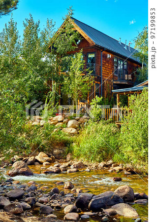 Vertical cabin next to small creek water and lush green forest of aspen Vertical cabin next to small creek water and lush green forest of aspen 97199853