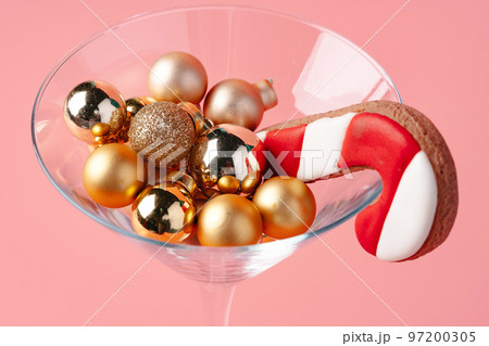Glass with Christmas decorations on pink pastel background 97200305