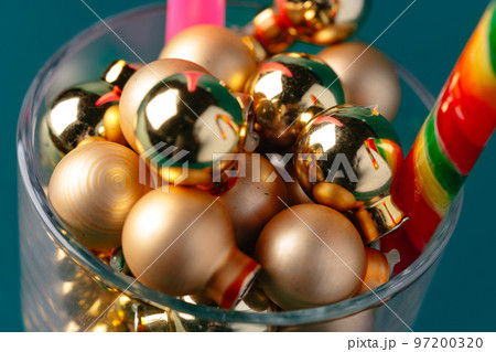Glass with Christmas decorations on dark green background 97200320