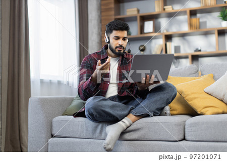 Young bearded businessman working on computer, talking online using a headset Young bearded businessman working on computer, talking online using a headset 97201071