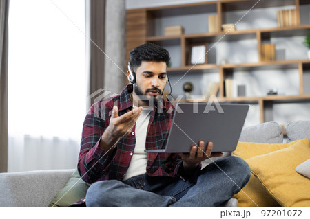 Closeup of young student man in wireless headset watching online lesson on laptop 97201072