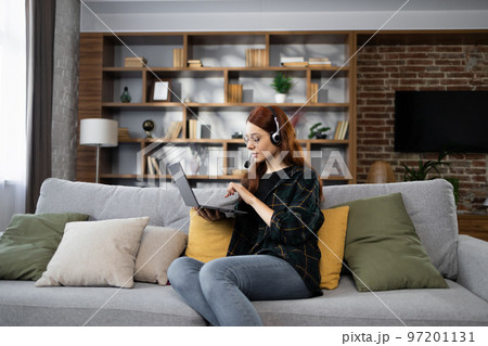 Young red hair business woman working on computer, talking online using a headset 97201131