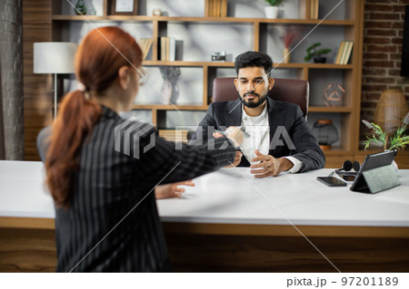 Back view of young red hair businesswoman giving bribe to smiling confident bearded businessman 97201189