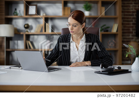 Young pretty businesswoman typing on laptop during work in office. Young pretty businesswoman typing on laptop during work in office. 97201482