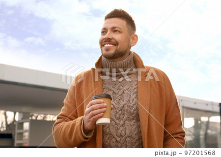 Man with cup of coffee on city street in morning 97201568