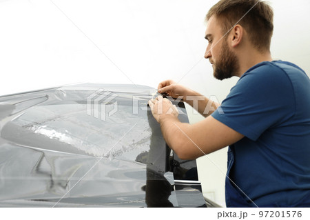 Worker tinting car window with foil in workshop Worker tinting car window with foil in workshop 97201576